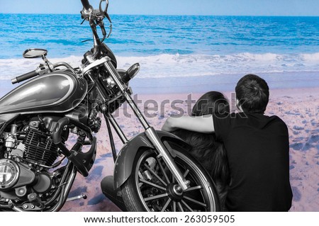 Black and White Young Romantic Couple Sitting next to Motorcycle on Color Sandy Beach Admiring Waves on Shore