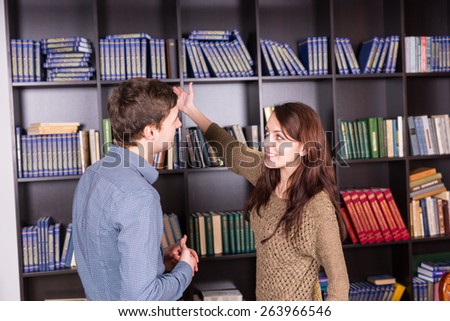 Happy Young Couple Standing Inside the Library Looking Each Other While Deciding What Book to Read.
