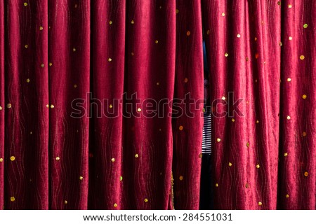 Little boy lurking behind the stage curtains peering through the gap waiting for his cue to come out on stage during a performance