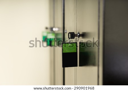 Key and attached label in a lock on a metal cabinet viewed from the side with a green tag and copyspace on the label in a safety and security concept
