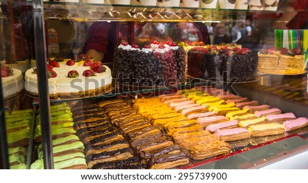 Glass Bakery Display Case Filled with Gourmet Desserts - Selection of Decadent Cakes and Colorful Iced Pastries in Bakery Window