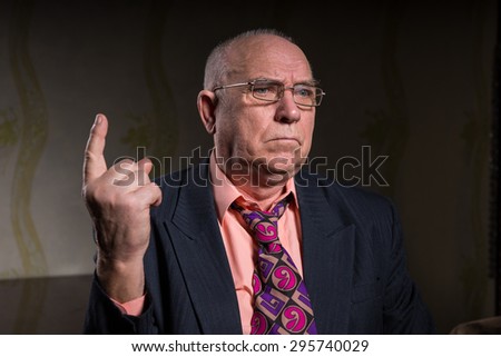 Close up Senior Bald Businessman in Formal Attire, Pointing his Finger Up While Looking Into Distance with Serious Facial Expression.