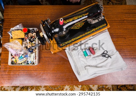 High Angle View of Old Fashioned Sewing Machine on Wooden Table Surrounded by Tailoring Seamstress Supplies