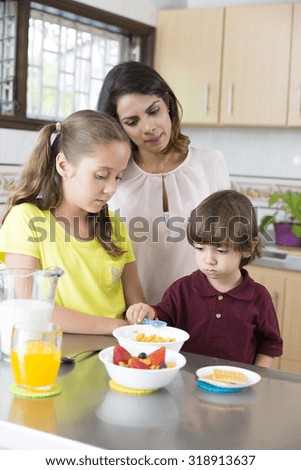 Lovely Mother and her children having breakfast in kitchen