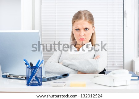 Portrait of young angry businesswoman sitting in her office,Angry businesswoman