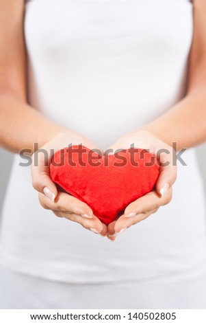 Woman holding red heart pillow in hands,Red heart