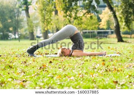 Young woman practicing yoga in the park,Yoga-Halasana/Plow pose
