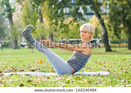 Young woman practicing yoga in the park,Yoga-Boat Pose - Navasana