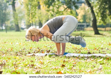 Young woman practicing yoga in the park,Yoga-Bakasana /Crane pose