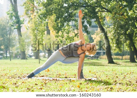Young woman practicing yoga in the park,Yoga-Virabhadrasana  /Rotated warrior pose