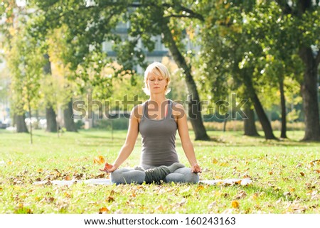 Young woman practicing yoga in the park,Yoga-Ardha Padmasana/Half-lotus pose