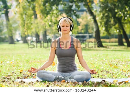 Young woman is listening music in the park and relaxing after exercise,Relaxation with music