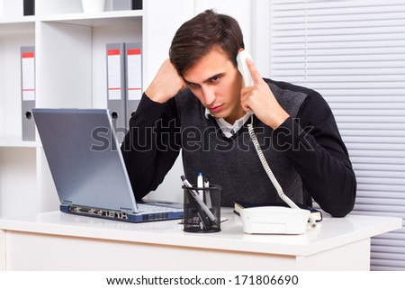 Worried businessman sitting in his office and talking on the phone,Concerned businessman