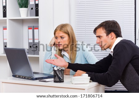 Businessman is sitting in office with his secretary and he is very angry at her because of something.