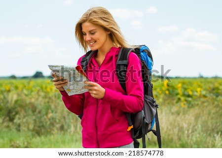 Cheerful blonde woman with backpack  is looking at her map  which way to go,Orientation