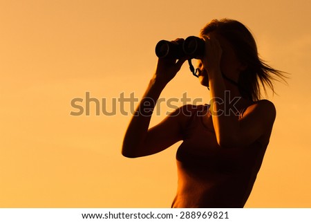 Silhouette of a woman  standing and watching sunset with binoculars.Enjoying in sunset  with binoculars