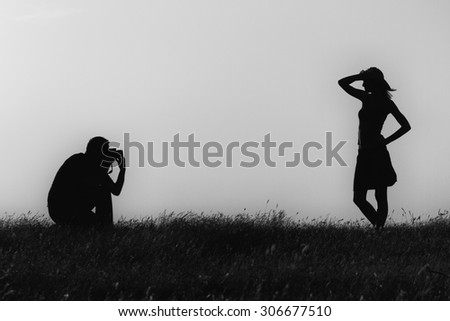 Silhouette of a man photographing woman outdoor.Silhouette of a man photographing woman\
Image is intentionally with grain and toned.