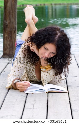 outdoor portrait of a beautiful woman reading a book