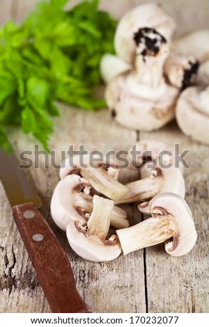 fresh sliced champignons with parsley and old knife on old wooden table