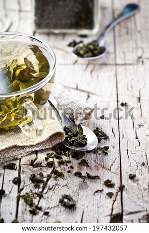 cup of green tea and spoons on rustic wooden board