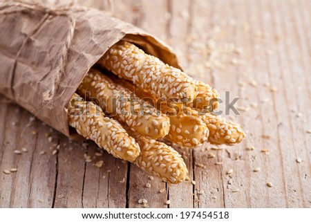 bread sticks grissini with sesame seeds in craft pack on rustic wooden background