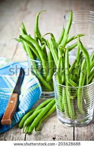 green string beans in glasses, napkin and knife closeup on rustic wooden background