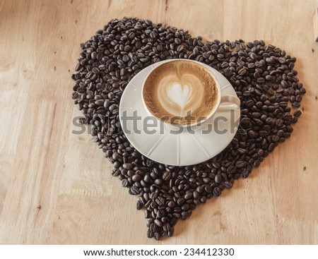 Coffee cup with coffee bean heart on table