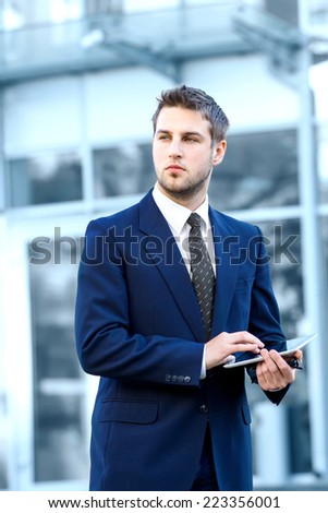 Businessman using a digital tablet computer, standing in front of his office.