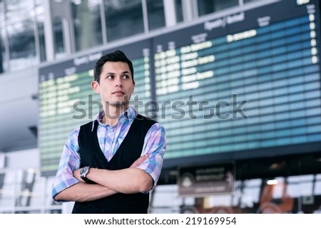 Man with serious look on a background of departure board at airport.