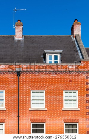 Closeup of a town house showing roof,  chimney, tv antenna and loft conversion
