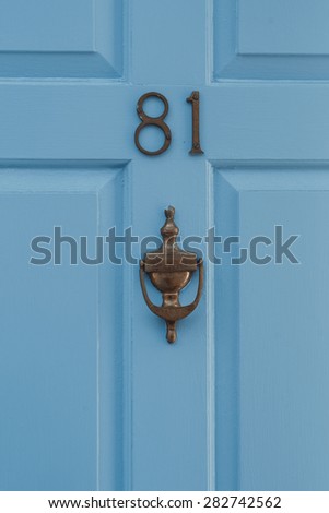 Eighty One 81 door number and knocker on blue painted wooden door closeup
