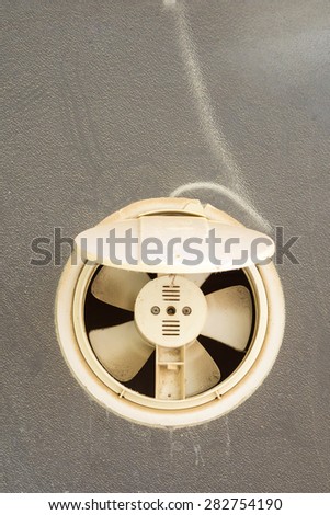 Dusty exhaust fan mounted in a glass window closeup
