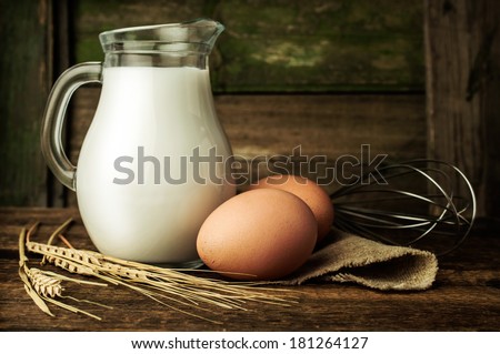Baking ingredients : milk, eggs and wheat on wooden