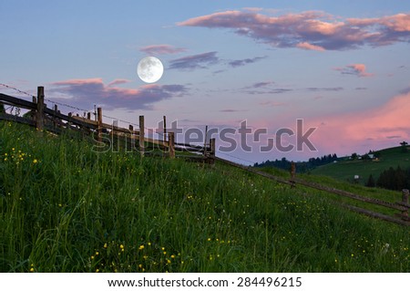 Rural landscape with a full moon at sunset