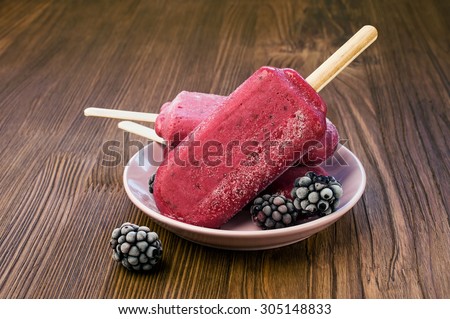 Ice lolly with blackberries on a wooden