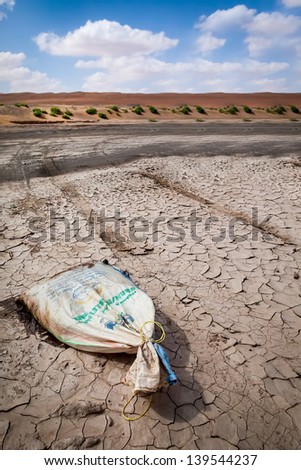 OMAN - DECEMBER 11: Full bag of flour on dried land, just few steps in front of Wahiba desert, in Oman on December 11, 2011. Despite technology food must be transferred into Wahiba by cars or camels.