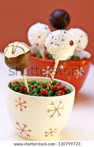 Snow flake containers filled with home made cake pops decorated for the holiday with red background standing in red and green candies