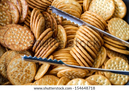 Serving platter filled with round salty crackers and silver tongs