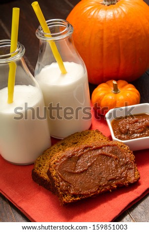 Slices of pumpkin bread with pumpkin spread sitting on orange napkin with 2 glasses of milk with yellow straws