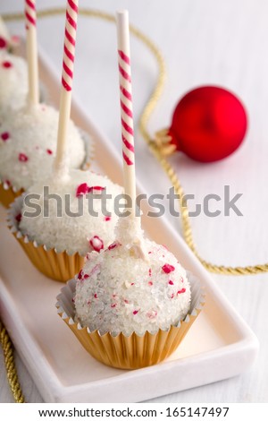 Row of peppermint brownie cake pops standing gold glitter cups on white plate with gold ribbon