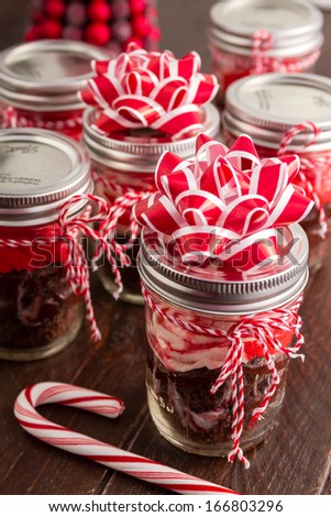 Chocolate peppermint cupcakes in a jar with red and white bakers twine, red bows and candy cane