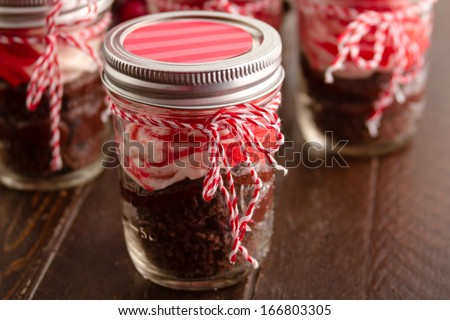 Chocolate peppermint cupcakes in a jar with red and white bakers twine on old brown table