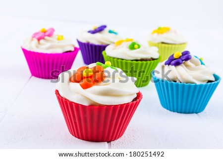 Brightly colored springtime flower chocolate cupcakes on white background