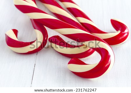 4 large red and white striped candy canes sitting on white wooden table