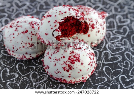 Red velvet cake balls with red sugar sprinkles sitting on black chalk board heart background