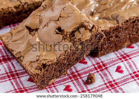 Close up of homemade double chocolate chunk brownies sitting on white checked napkin with red hearts
