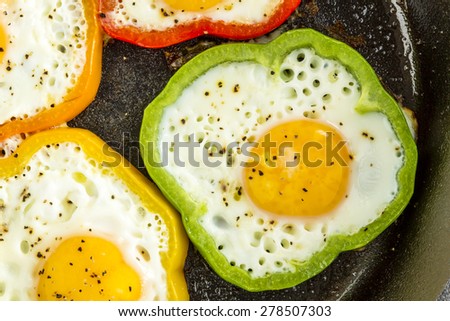 Close up of large cast iron skillet with fried eggs in green, yellow, red and orange bell peppers
