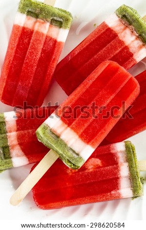 Close up of frozen fresh fruit watermelon and kiwi popsicles sitting on white plate