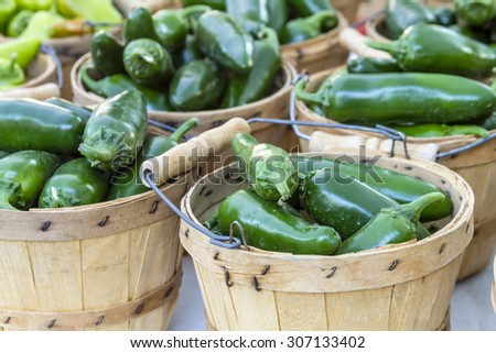 Fresh organic jalapeno peppers in brown bushel baskets sitting on table at local farmers market