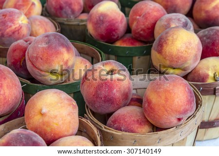 Fresh organic yellow peaches in brown bushel baskets for sale at local farmers market